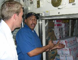 Mess Specialist Rahmel Leake shows chef Ricky Wallenburg of Perth’s Rendezvous Observation City Hotel a stocked freezer onboard USS Shiloh.